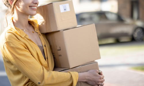 Woman carrying a stack of cardboard boxes